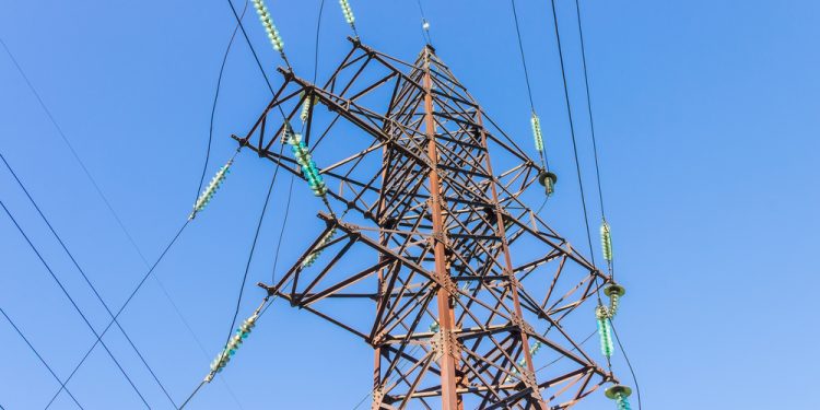 Metallic pole of high-voltage power line with insulators and wires on a background sky