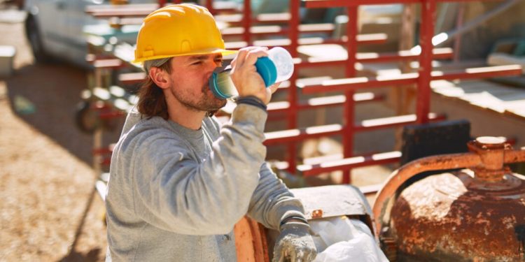 Construction worker on a heavy site doing hard work and drinking water.