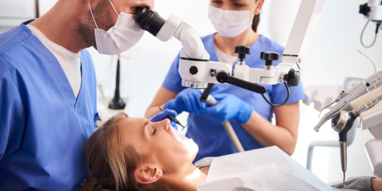 Male dentist working with dental microscope