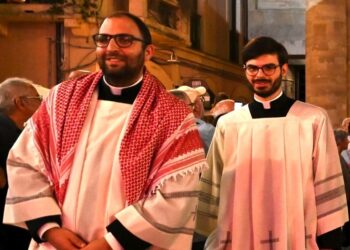 In processione con la kefiah sull’abito talare, don Alessio: è simbolo di solidarietà e pace